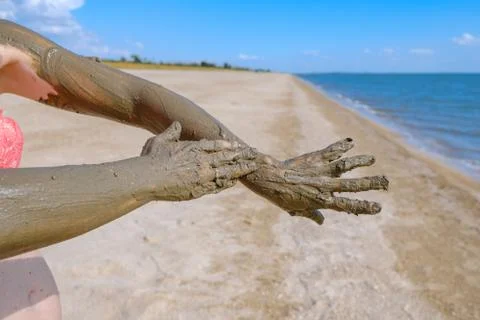 Selective focus on hands in curative mud on the background of the sea beach. Stock Photos