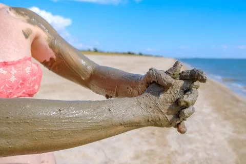 Selective focus on hands in curative mud on the background of the sea beach. Stock Photos
