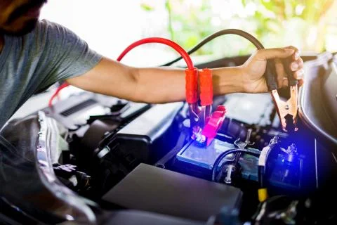 Selective focus hands do charging car battery with electricity through cables Stock Photos