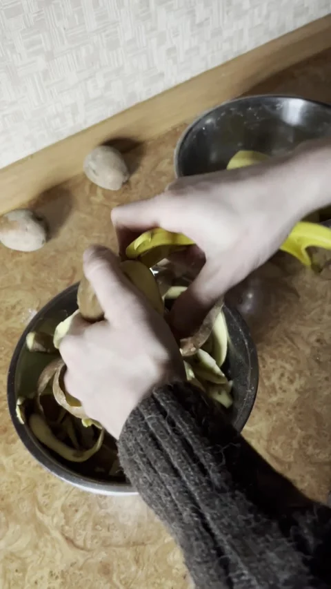 Selective focus hands peeling potatoes Stockbeeldmateriaal 334327509