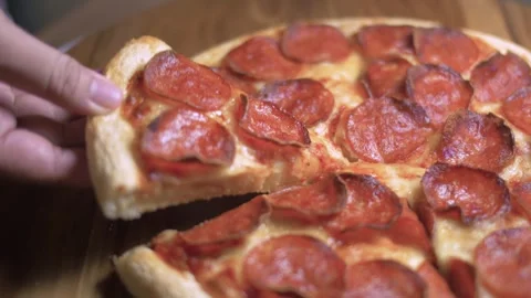 Selective focus of Hands take slices of pepperoni pizza from a wooden table.. Stock Footage 309122347
