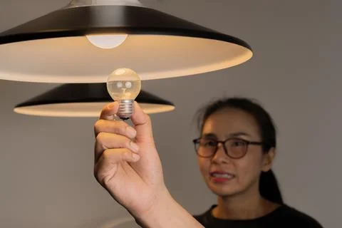 Selective focus of handsome man hand changing light bulb near attractive gi.. Stock Photos