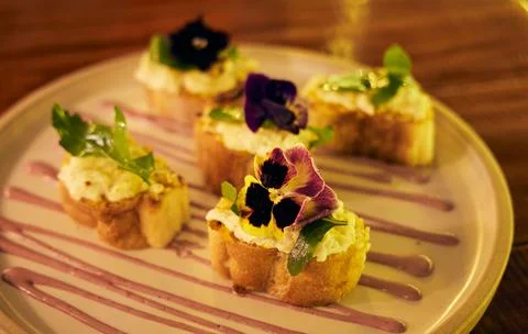 Selective focus of herbed deviled egg bruschetta with a flower on the top served Stock Photos