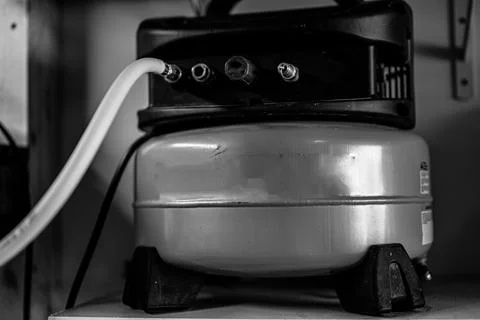 Selective focus on a hose connected to a Pancake air compressor sitting on a Stock Photos