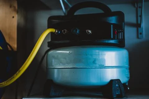 Selective focus on a hose connected to a Pancake air compressor sitting on a Stock Photos