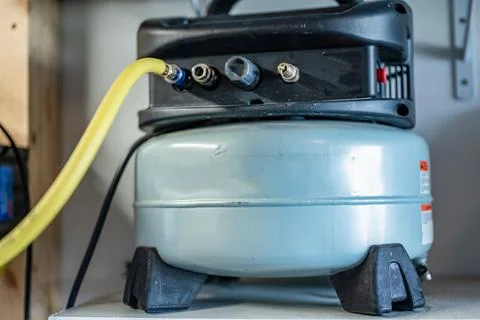 Selective focus on a hose connected to a Pancake air compressor sitting on a Stock Photos
