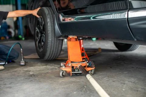 Selective focus to hydraulic floor jack with blurry hand of professional me.. Stock Photos