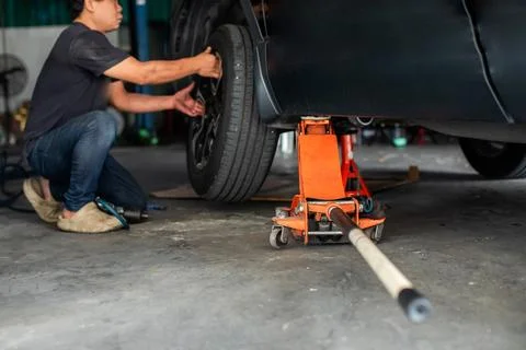 Selective focus to hydraulic floor jack with blurry professional mechanic i.. Stock Photos