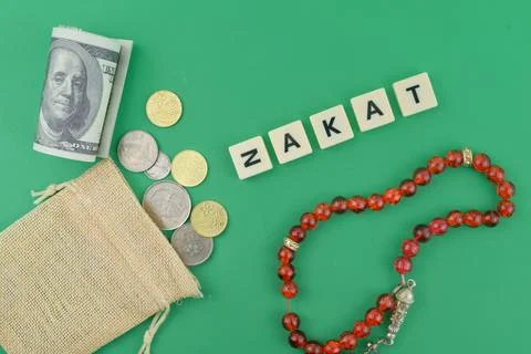 Selective focus image of bank note,coin,read beads and zakat wording on green Stock Photos