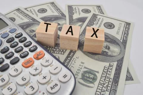 Selective focus image of calculator and usd bank note with tax wording. Stock Photos