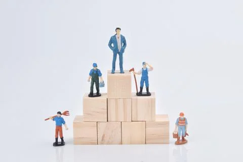Selective focus image of group of miniature people standing on a wooden block Stock Photos