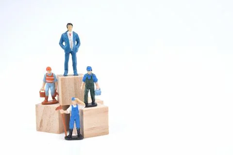 Selective focus image of group of miniature people standing on a wooden block Stock Photos