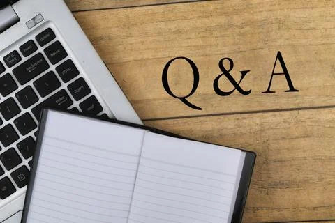 Selective focus image of laptop and notebook with Q n A wording on a wooden b Stock Photos