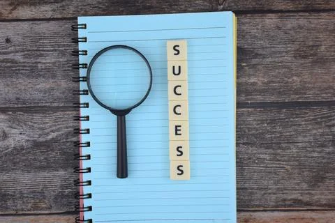 Selective focus image of magnifying glass with SUCCESS wording on a paper. Mo Stock Photos
