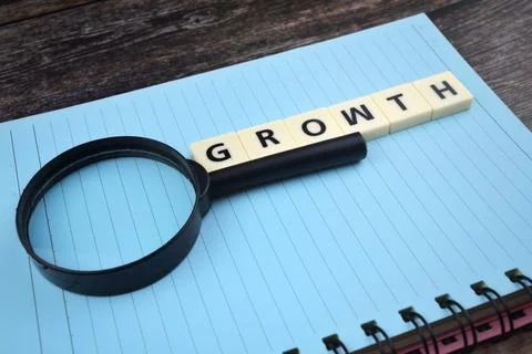 Selective focus image of magnifying glass with GROWTH wording on a paper. Mot Stock Photos