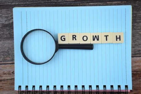 Selective focus image of magnifying glass with GROWTH wording on a paper. Mot Stock Photos