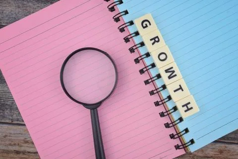 Selective focus image of magnifying glass with GROWTH wording on a paper. Mot Stock Photos