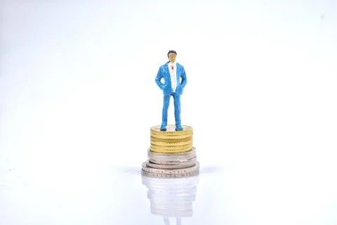 Selective focus image of miniature rich people standing on coin money. Busine Stock Photos