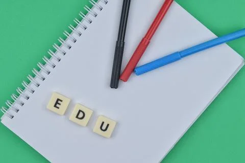 Selective focus image of pen and notebook on green background with edu wordin Stock Photos