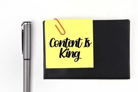 Selective focus image of pen and sticky note with content is king wording. Stock Photos