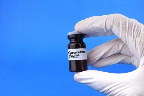 Selective focus image of person holding coronavirus vaccine bottle with glove Stock Photos