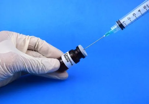 Selective focus image of person holding coronavirus vaccine and syringe. Medi Stock Photos