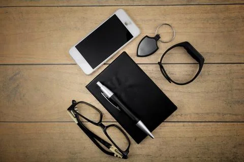 Selective focus image of spec, pen,phone, smartwatch and book on a wooden bac Stock Photos