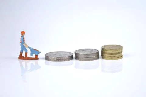 Selective focus image of working person miniature with stack of coins on a wh Stock Photos