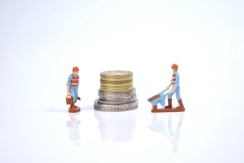 Selective focus image of working person miniature with stack of coins on a wh Stock Photos