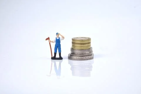 Selective focus image of working person miniature with stack of coins on a wh Stock Photos