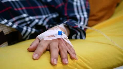 Selective focus of Infusion pump feeding IV drip into patients arm Stock Footage 281576529