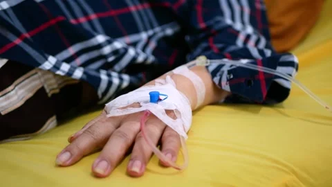 Selective focus of Infusion pump feeding IV drip into patients arm Stock Footage 281576896