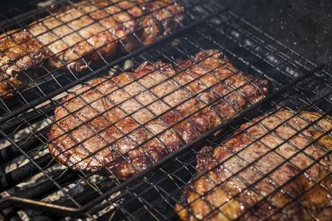Selective focus of juicy beef steaks grilling on barbecue grid with smoke Stock Photos