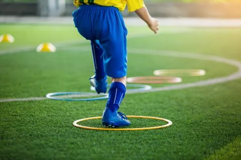 Selective focus to kid soccer player Jogging and jump at ring ladder marker o Stock Photos