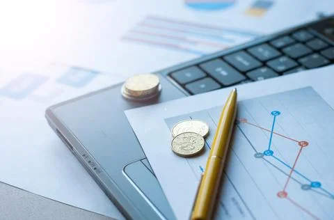 Selective focus of laptop, coins, papers, glasses, pen and calculator on tabl Stock Photos