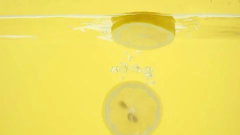Selective focus of lemon slices floating in clear water, slow motion 库存影片 153479293