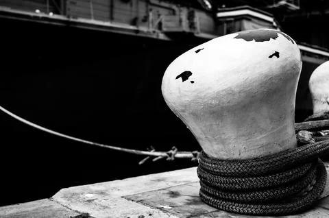 Selective focus on line securing a naval boat to a port bollard. Stock Photos
