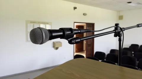 Selective focus on lone microphone ready for speaker in vacant auditorium Stock Footage 313713659