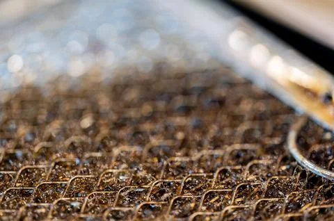 Selective focus macro of a dirty kitchen range hood filter clogged with grease. Stock Photos