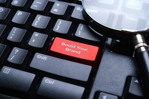 Selective focus of magnifying glass on a computer keyboard with red button .. Stock Photos