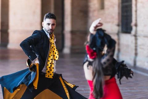 Selective focus on a man with a cape dancing flamenco with a woman outdoors Stock Photos