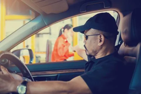 Selective focus to the man driving the car is paying the expressway 스톡 사진