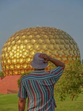 Selective focus on a man who is looking towards the Matrimandir temple in Aur Foto stock