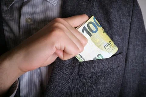 Selective focus of man's hand in close-up puts a wad of euros into his jack.. Stock Photos