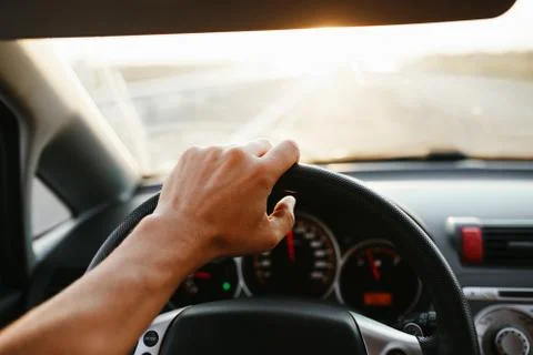 Selective focus man's hand on steering wheel, driving a car at sunset. Travel Stock Photos
