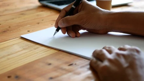Selective focus of a man's hand writing on a white paper on a table Stock Footage 103492674