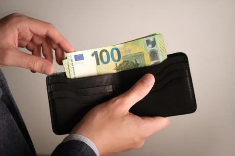 Selective focus of man's hands fold euro banknotes into a wallet Foto stock