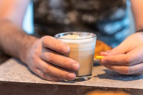 Selective focus on a man's hands, a glass of coffee in one hand and a capsule of Stock Photos