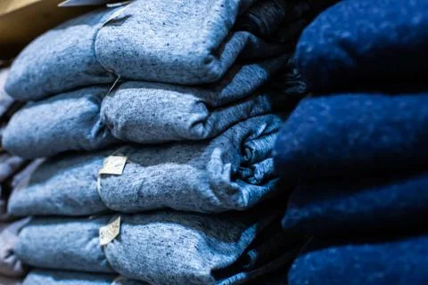 Selective focus to many clothes folded in the shop. Many stack of clothes. Stock Photos