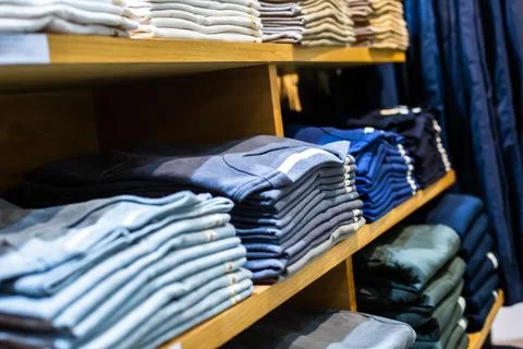 Selective focus to many clothes folded in the shop. Many stack of clothes. Stockfoto's